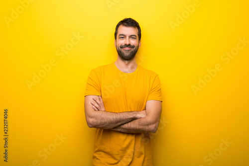 Man on isolated vibrant yellow color keeping the arms crossed in frontal position
