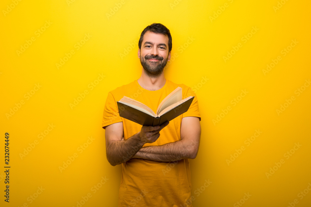 Man on isolated vibrant yellow color holding a book and giving it to someone Man on isolated vibrant yellow color holding a book and giving it to someone