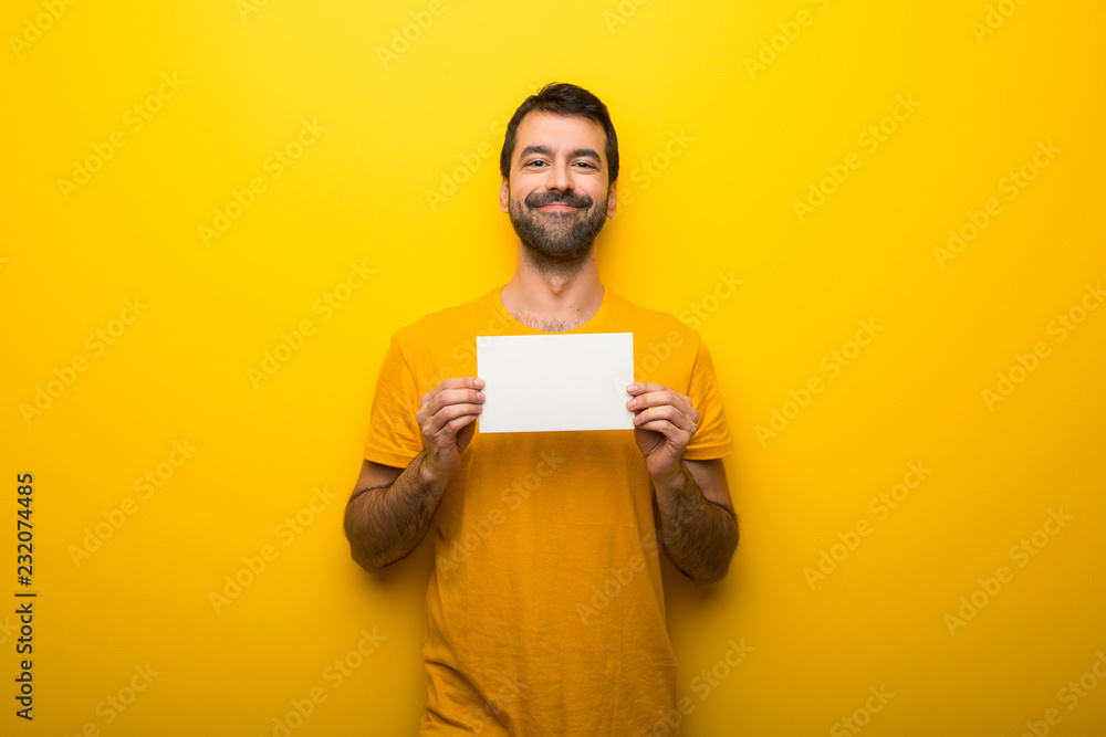 Man on isolated vibrant yellow color holding an empty white placard for insert a concept Man on isolated vibrant yellow color holding an empty white placard for insert a concept
