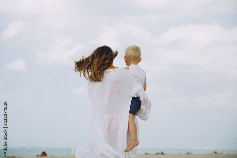 Young mother carrying her little son at the beach