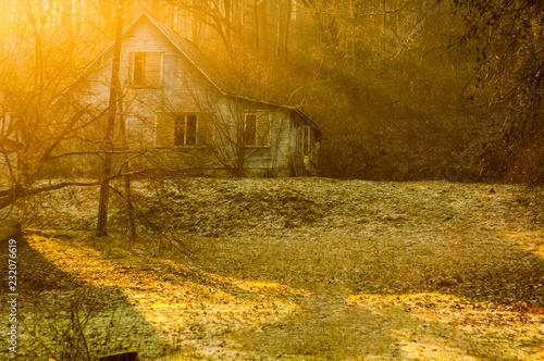Abandoned old wooden house in the forest. Sun rays. Autumn day