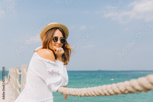 Young woman relaxing at pier at the beach and looking into the camera