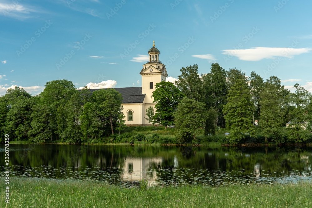 Beautiful view of a white church by the river surrounded by lush green trees Beautiful view of a white church by the river surrounded by lush green trees
