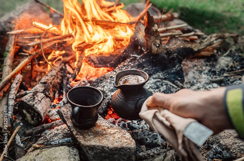 Luxury camping concept. Fresh coffee prepared in turkish cezva on campfire coals.