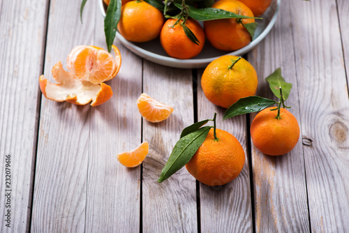 Tangerines, mandarins, fresh citrus fruits with leaves on wooden background