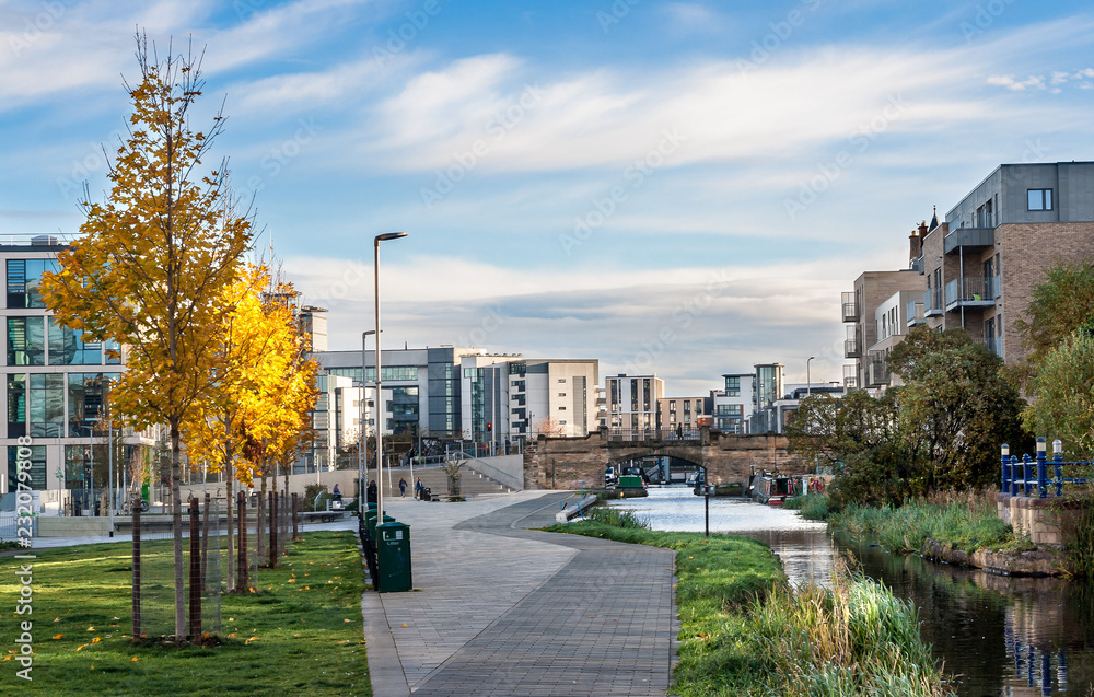 Obraz premium Cityscape of Edinburgh, Scotland, showing Union Canal walkway with autumnal yellow trees on the side, Viewforth bridge in the background and modern buildings around. Urban landscape. Architecture