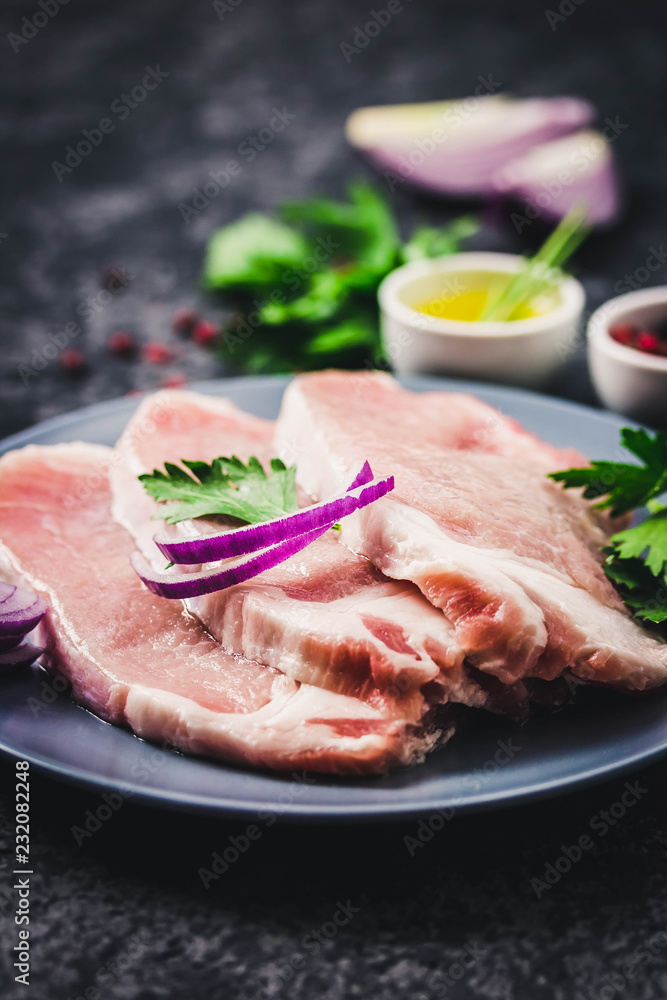 Raw fresh meat slices on plate, dark background. Selective focus, space for text. Raw fresh meat slices on plate, dark background. Selective focus, space for text.