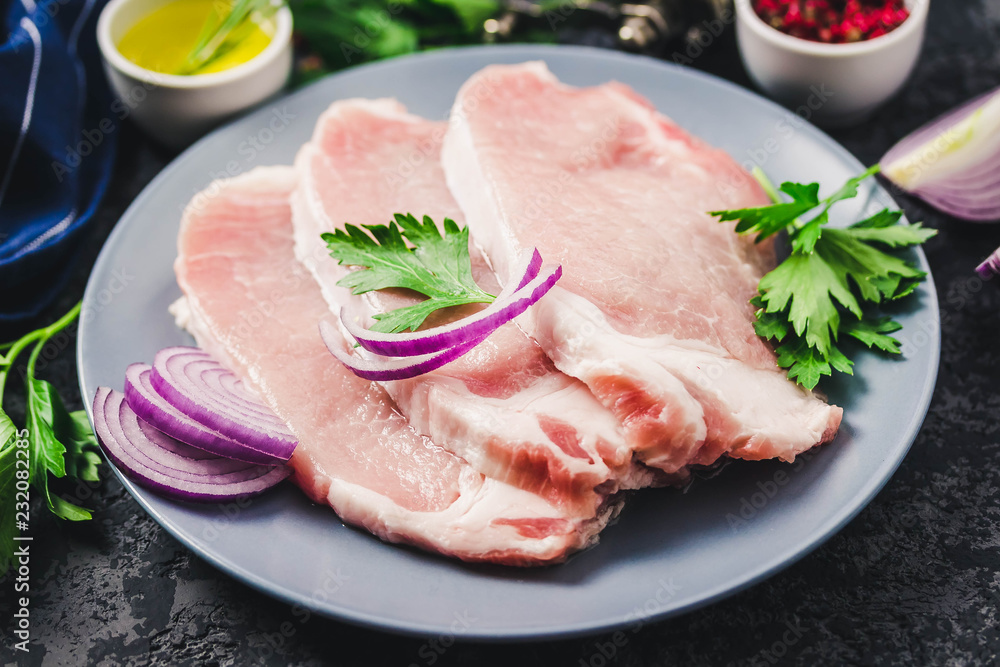 Raw fresh meat slices on plate, dark background. Selective focus, space for text. Raw fresh meat slices on plate, dark background. Selective focus, space for text.
