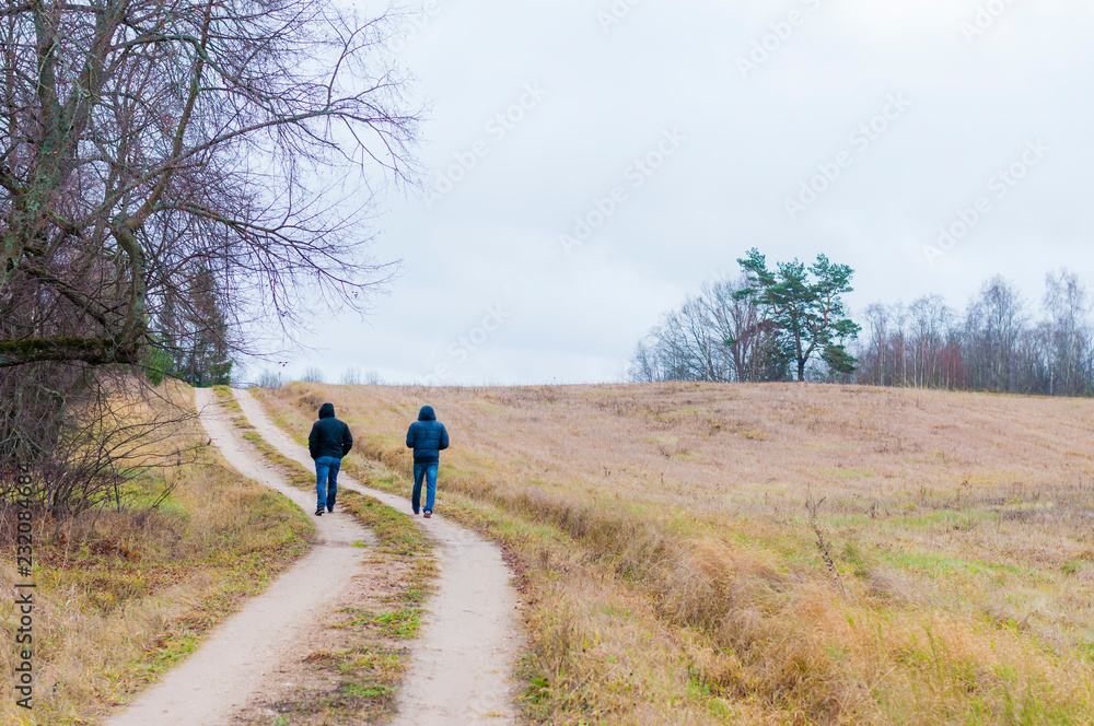 Two men walking by the bent rural road