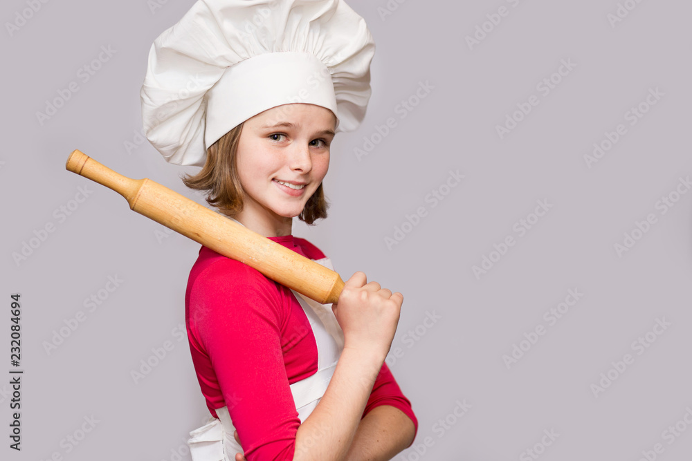 Children cook. Happy little girl in chef uniform holds rolling pin isolated on white background. Children cook. Happy little girl in chef uniform holds rolling pin isolated on white background.