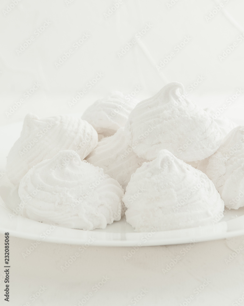 Delicate, white, fruit marshmallows. On a white background in a white plate. Isolated. Blurred background.