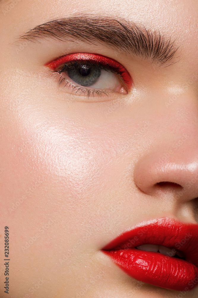 Obraz premium Closeup of beauty woman with clean shiny skin and bright makeup. Fashion, spa, cosmetology, injections into red lips, shadows on brown eyes and thick eyebrows, cosmetics, makeup, beautiful