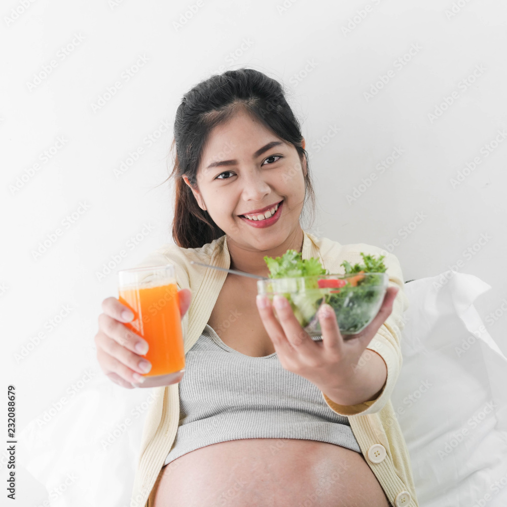 Asian pregnant woman showing eating fruit salad and a glass of orange juice in her hands, lifestyle concept. Asian pregnant woman showing eating fruit salad and a glass of orange juice in her hands, lifestyle concept.