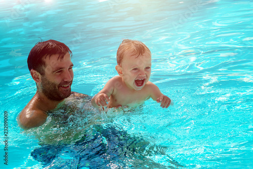 Father and child are having fun in pool. Dad and son are swimming indoor pool. Father teachs son to swim. Concept of kids sport, family summer vacation. Concept of healthy holiday and family activity.