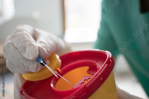 Doctor put syringe in red disposal boxes