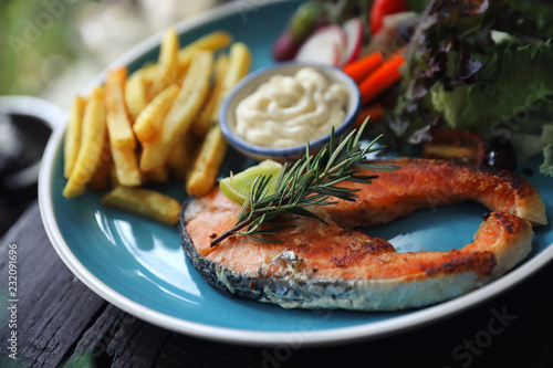 Roasted salmon steak , baked salmon with salad fresh vegetable pm wooden table