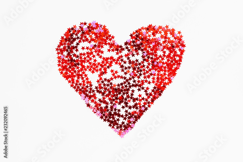 Heart made of sparkling red conffetti. Shining symbol of love on white background.