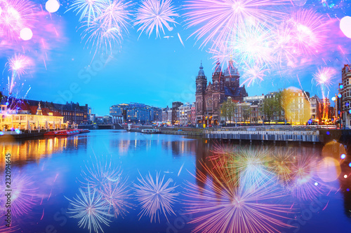 Amsterdam skyline with Church of St Nicholas over old town canal at night with fireworks, Amsterdam, Holland © neirfy
