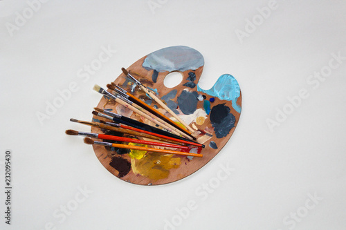 Palette with paints and brushes isolated on white
