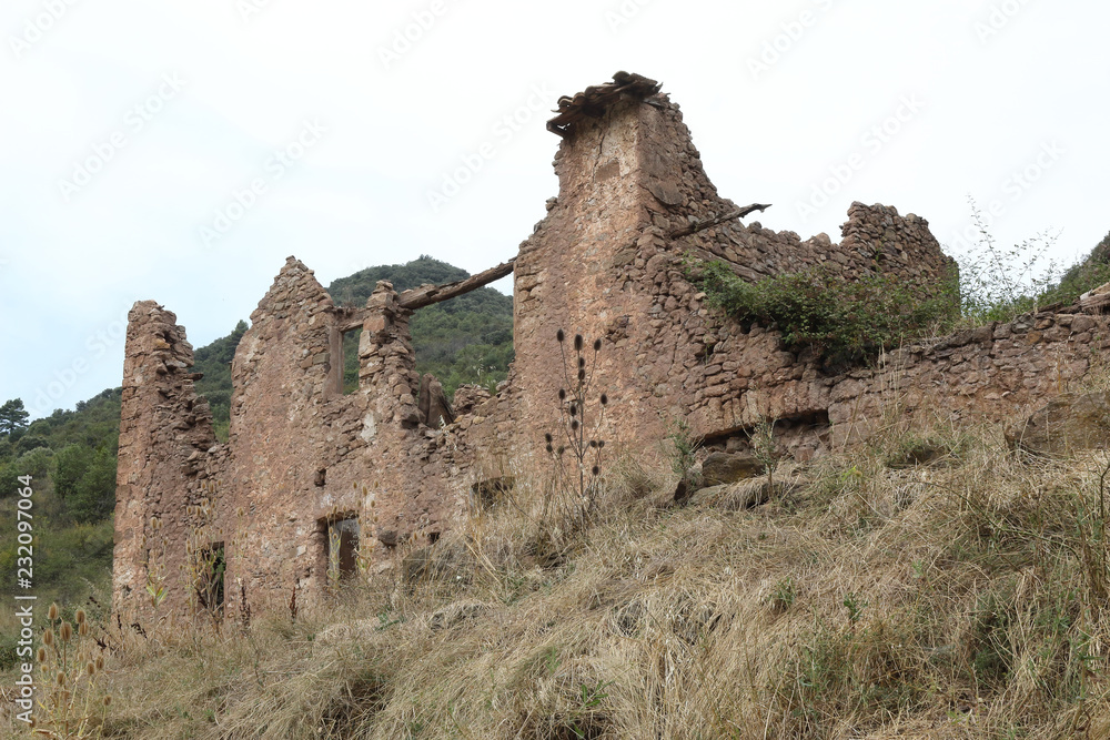 The remains of an old abandoned stone hut in the Pyrenees mountains in Mallos de Riglos, in Aragon region, Spain, during a cloudy autumn day The remains of an old abandoned stone hut in the Pyrenees mountains in Mallos de Riglos, in Aragon region, Spain, during a cloudy autumn day