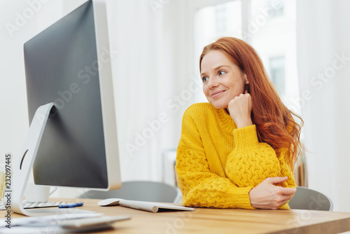 Young cheerful woman sitting in front of computer
