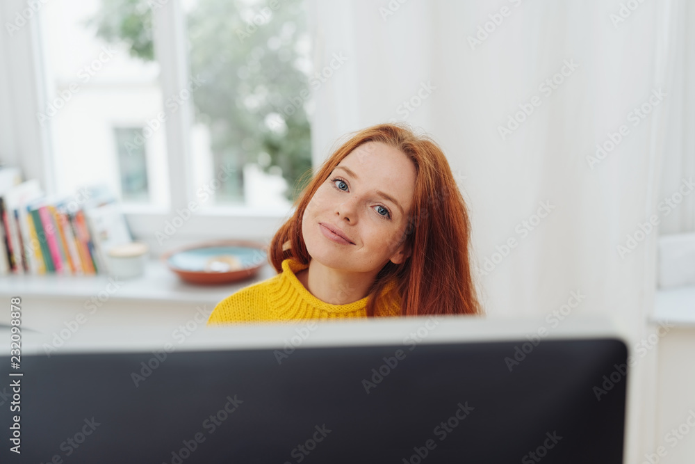 Smiling ginger girl sitting in front of monitor Smiling ginger girl sitting in front of monitor