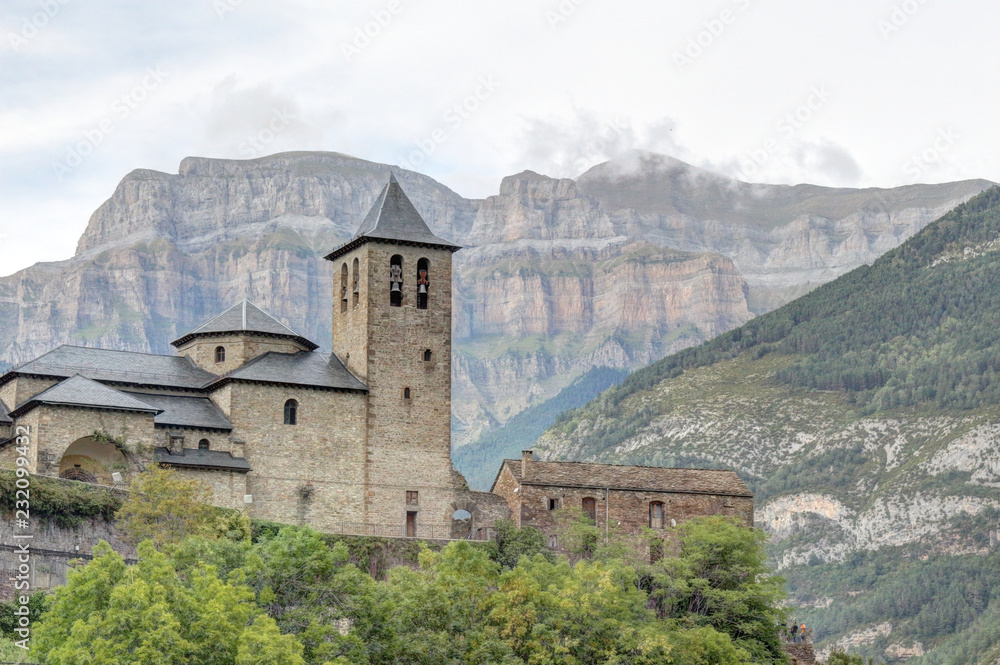 The rural small town of Torla, in the Aragon Pyrenees mountains in Spain, the romanesque church and the Pico Mondarruego range, at sunset