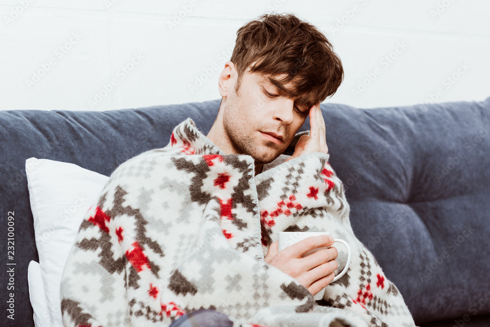 sick man wrapped in blanket sitting with cup of tea in bed at home sick man wrapped in blanket sitting with cup of tea in bed at home