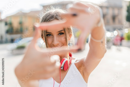 Portrait of smiling teenage girl making a finger frame in the city