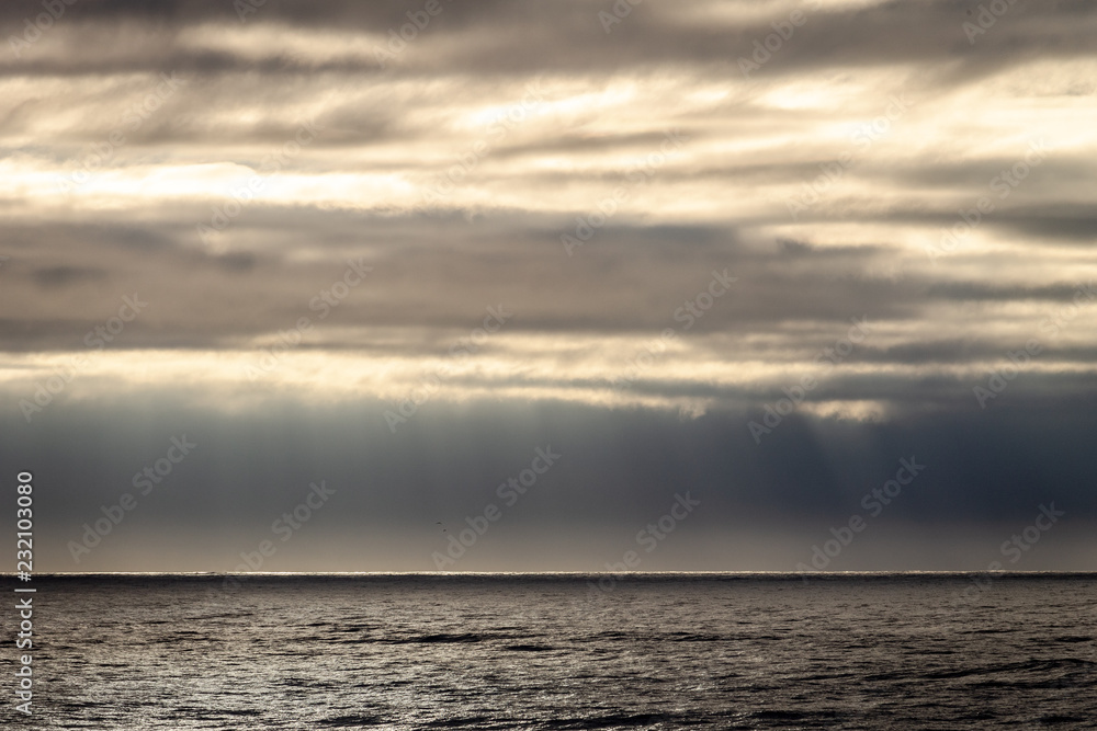 Obraz premium Sun Rays Through Clouds near the Ocean