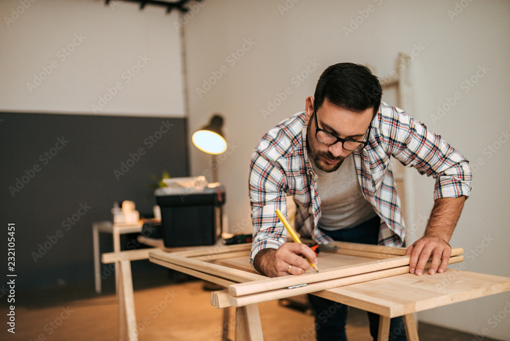 Young handsome man marking and measuring wood. Young handsome man marking and measuring wood.