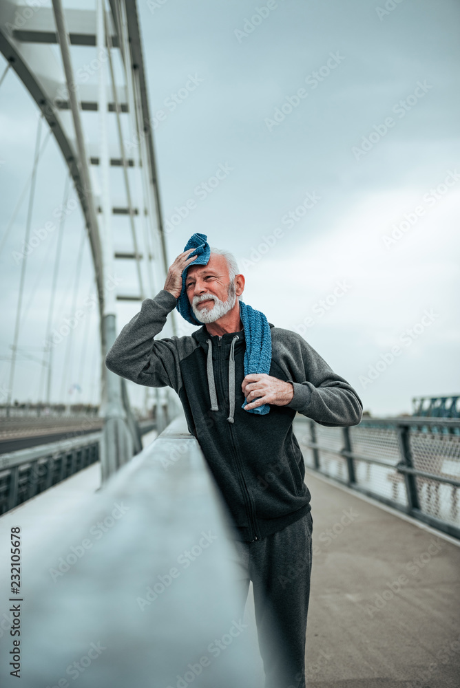 Senior athlete resting and wiping his sweat with a towel after workout. Senior athlete resting and wiping his sweat with a towel after workout.