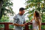Young couple drinking wine on terrace or balcony in forest.