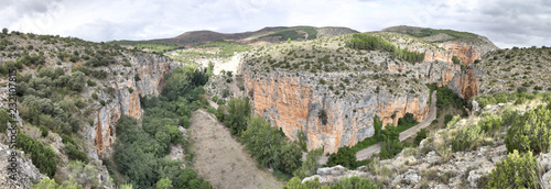 The Barranco de la Hoz Seca (Dry Defile Gully) canyon, with scarps, bushes and red rocks, in a cloudy atumn, in the Jaraba rural town, Aragon, Spain