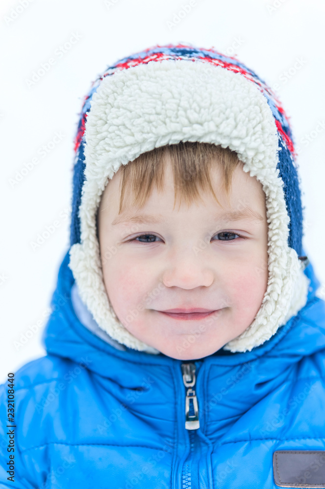 Outdoor portrait face of a little boy in a cap close-up in on the background snow winter Outdoor portrait face of a little boy in a cap close-up in on the background snow winter