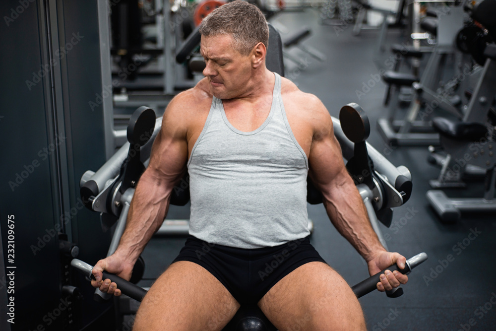 athletic man trains in the gym. Training of biceps athletic man trains in the gym. Training of biceps