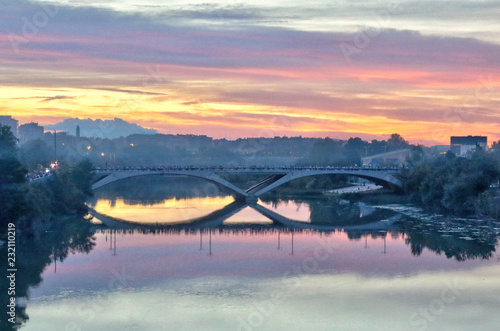 A landscape of the Santiago Bridge reflecting in the Ebro river at sunset, after a storm, in a cloudy autumn, in Zaragoza, Spain