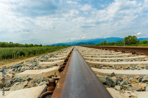 Railroad tracks leading to endless infinity. Meadow landscape and distant mountains. photo