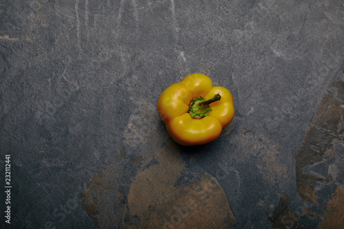 top view of yellow bell pepper on grey marble background photo