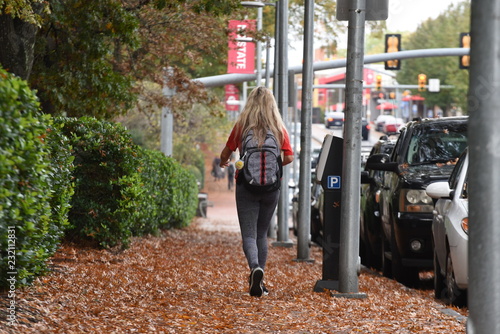 A blonde college girl walks through the leaves near NC State University.  photo