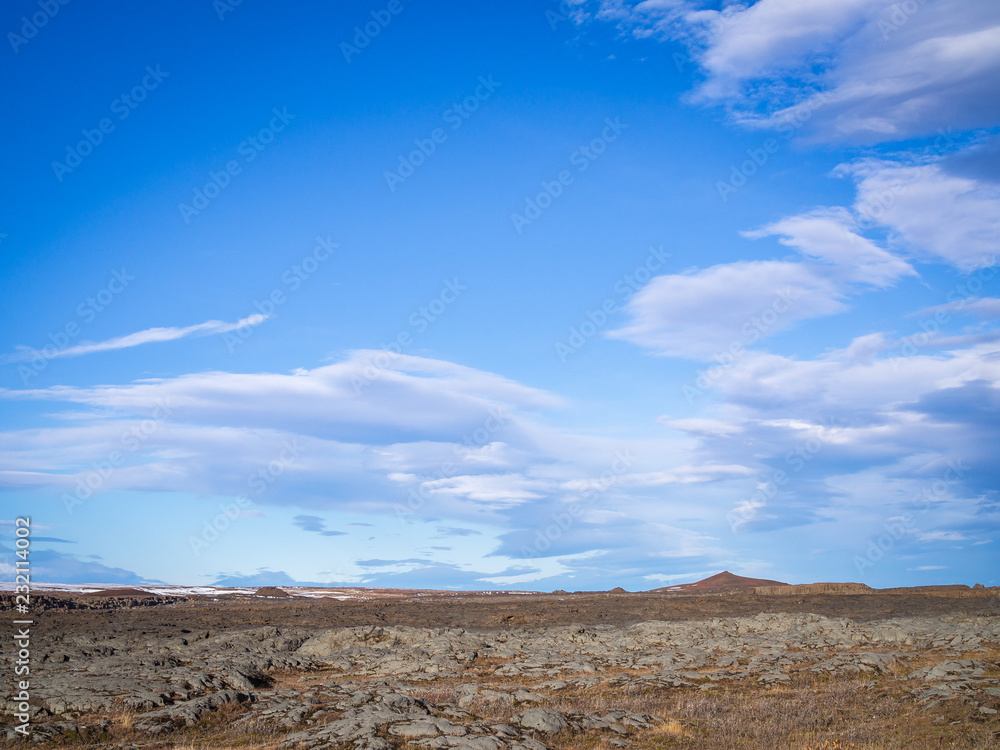 Typical Icelandic landscape with mountains top on horizon under blue cloudy sky
