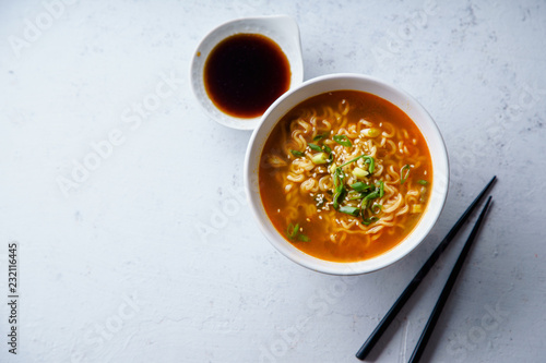 Overhead image of easy japanese ramen with noodles, pork broth, egg and leek in white bowl on concrete background with copy space