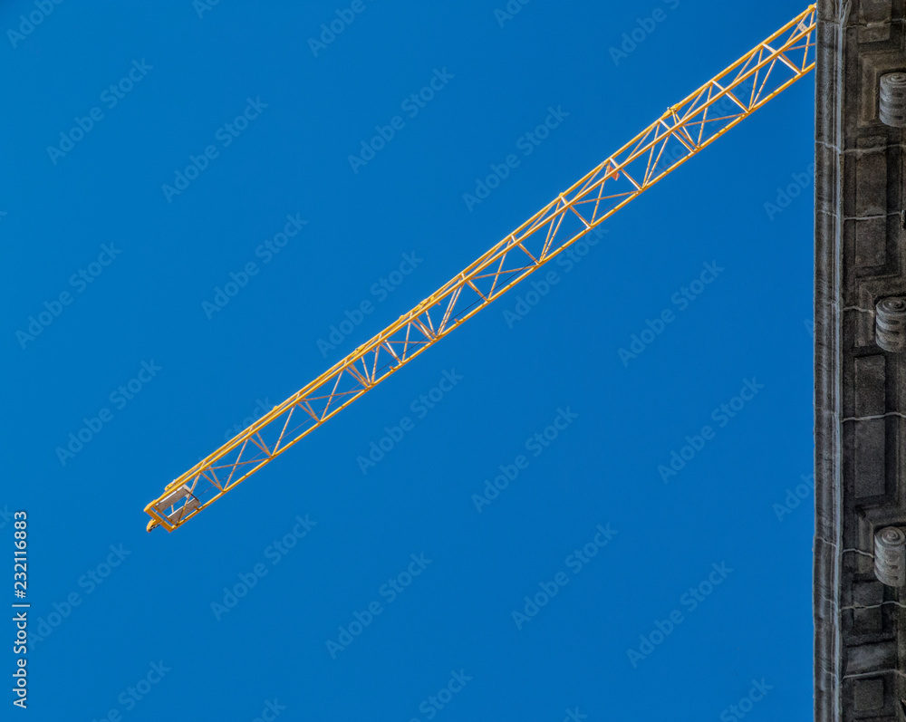 Fototapeta premium Construction crane tower on blue sky background. Crane and building working progress. 