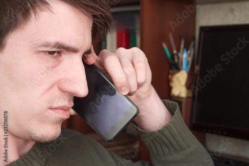 young guy talking on a black smartphone with a smile, good news photo