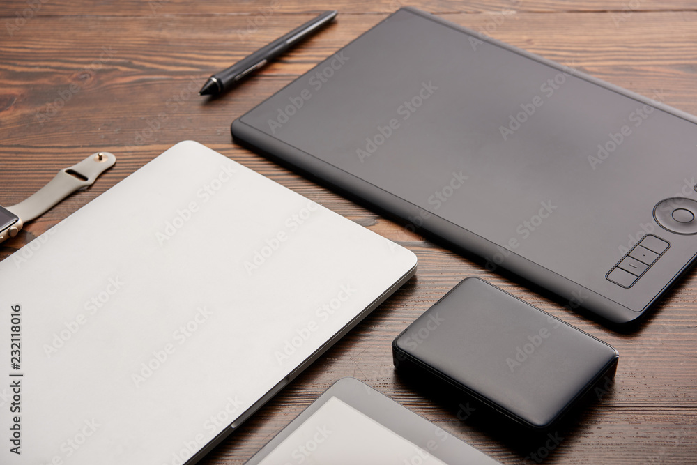 close-up shot of various wireless devices and graphics tablet on wooden desk close-up shot of various wireless devices and graphics tablet on wooden desk