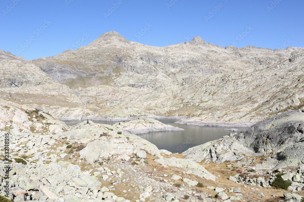 The upper Balchimaña artificial lake, among barren rocky mountains and a blue sky in a sunny autumn, in Panticosa, Aragon Pyrenees, Spain