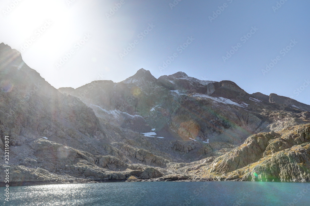 The lower Blue Lake (Ibon Azul), among barren rocky mountains with snow and a blue sky in a sunny autumn, in Panticosa, Aragon Pyrenees, Spain