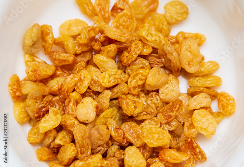 Yellow raisins in a plate as background