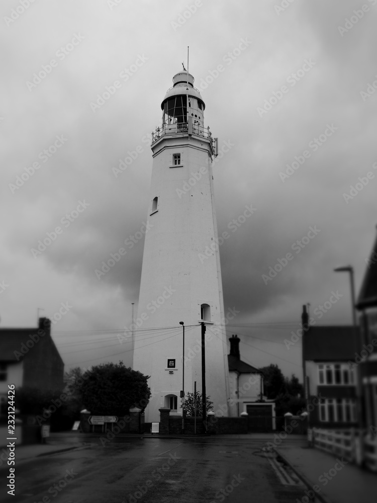 Withernsea Lighthouse, an inland lighthouse that stands in the middle of the town, taken on a stormy day with dark clouds and set against the background of blurred houses, shot in monochrome, UK