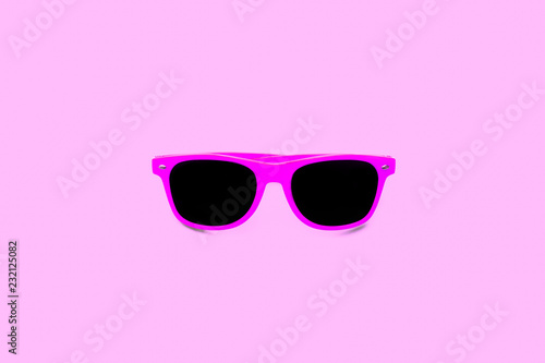 Summer pink sunglasses isolated in large seamless pink background. Minimal design element for sun protection, hot days, tropical travel, summer vacations and beach holidays.